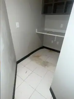 Small utility room with a wall shelf and stains and dust on the tile floor