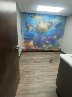 Commercial room with an underwater mural and debris on the floor before cleaning
