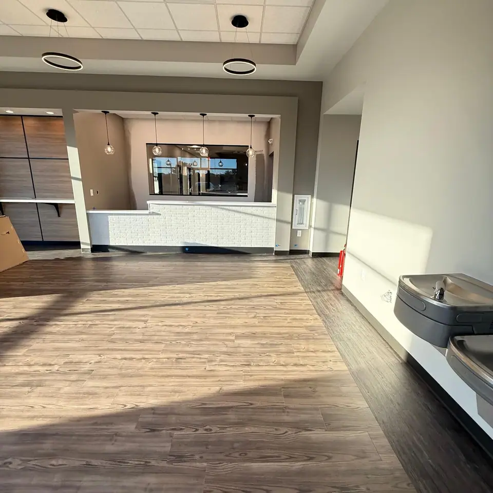 New commercial space with a service counter, pendant lights and wood-look floors after a final clean